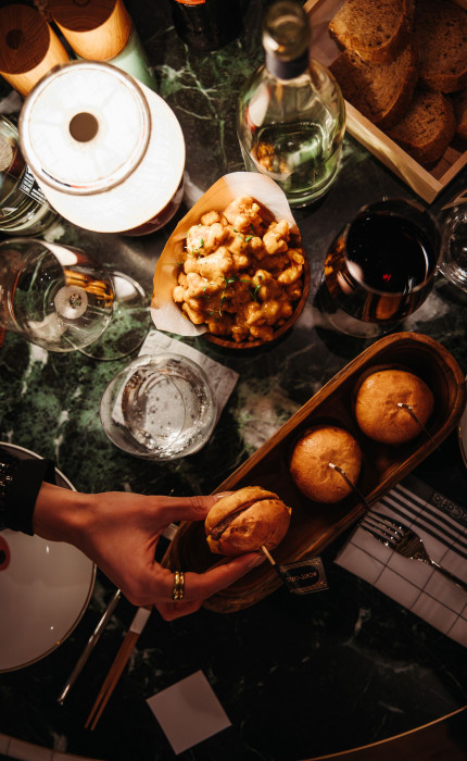 Beefbar, dunkelgrüner Marmortisch mit verschiedenen Gerichten und Getränken.