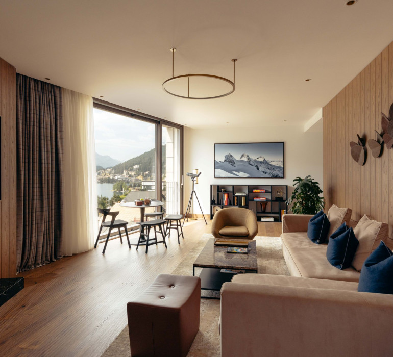 Grosszügiger Wohnbereich mit Kamin, Sofa, Sitzecke und Blick auf den St. Moritzersee.