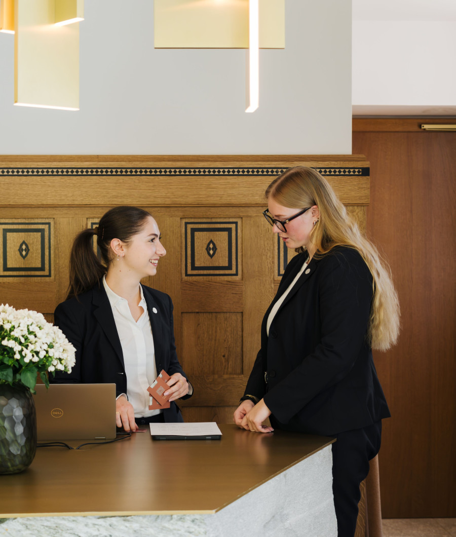 Zwei Personen stehen an der Rezeption.