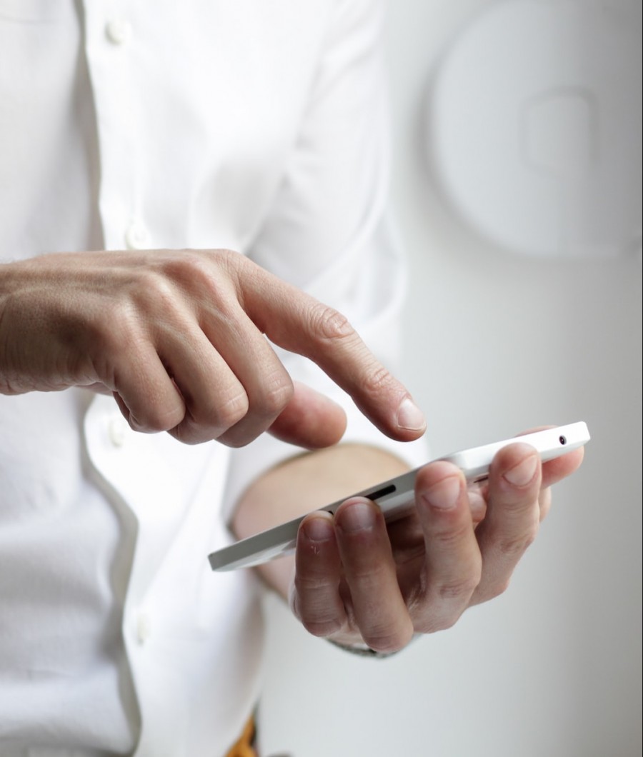 Ein Mann mit weißem Hemd der auf seinem Handy tippt