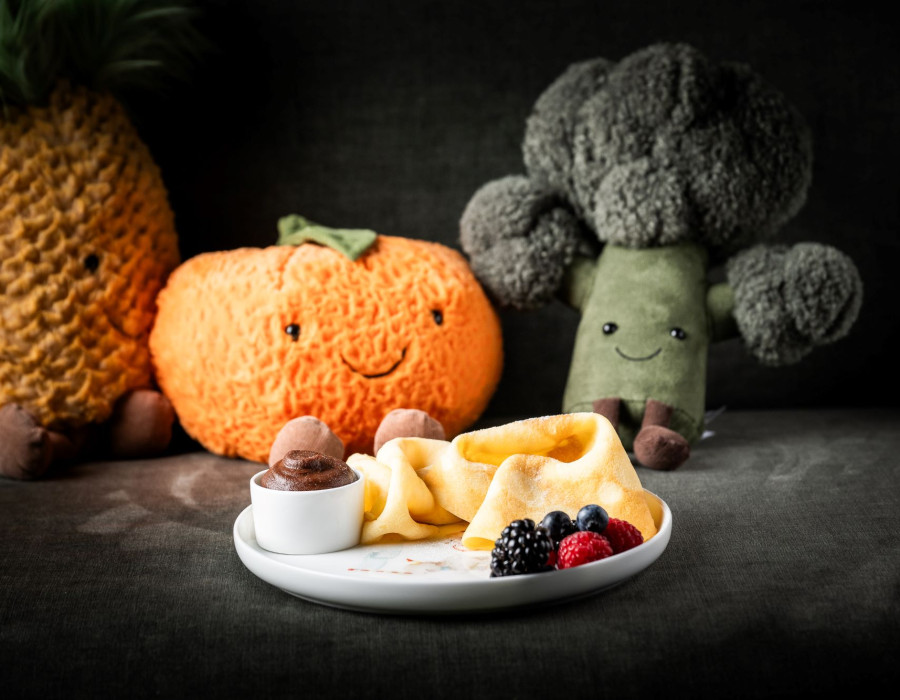 Eierkuchen serviert mit Beeren vor Kuscheltieren in Form von Obst und Gemüse